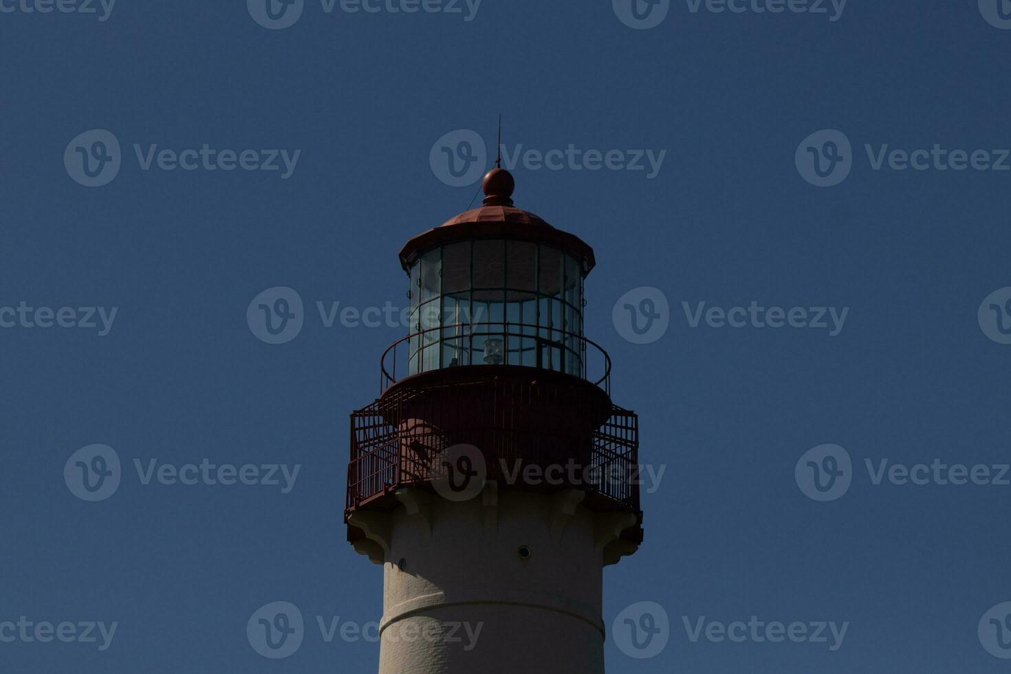 cette est le Haut image de cape mai point phare. le rouge métal Haut des stands en dehors contre le blanc brique de le la tour. photo