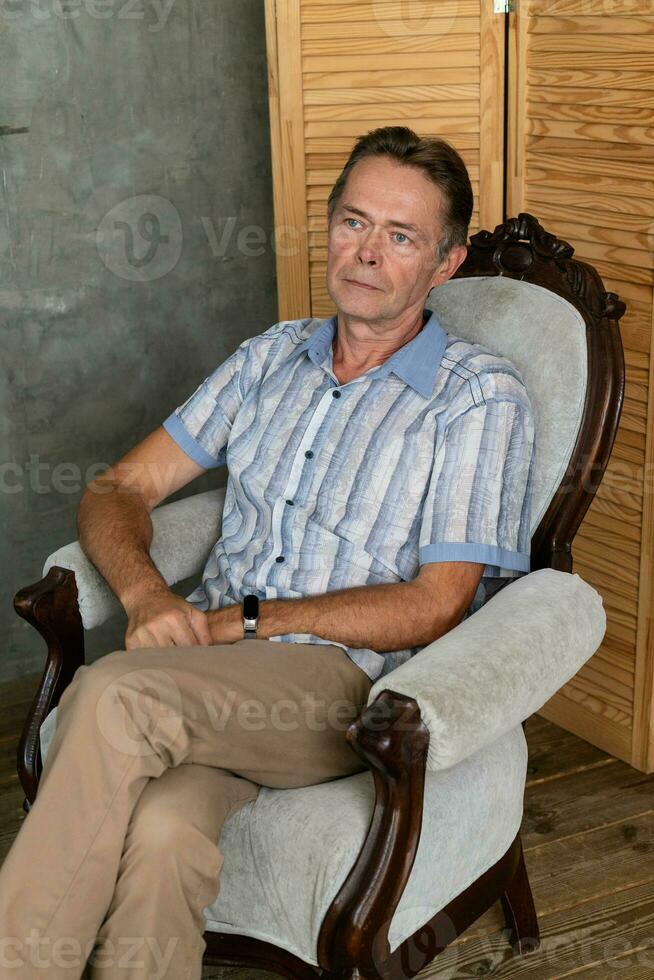 un vieux intelligent homme ayant une du repos sur une fauteuil photo