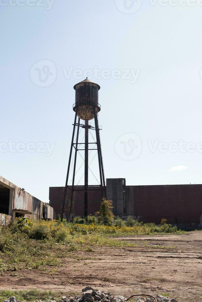 une magnifique l'eau la tour est ensemble autour un abandonné zone. cette rouillé métal structure des stands grand contre une bleu ciel. photo