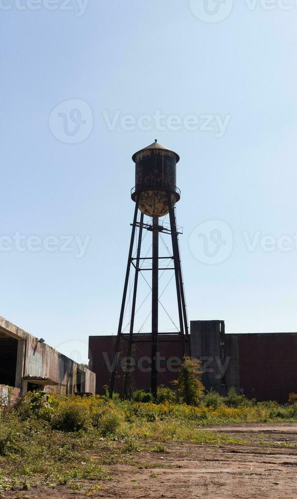 une magnifique l'eau la tour est ensemble autour un abandonné zone. cette rouillé métal structure des stands grand contre une bleu ciel. photo