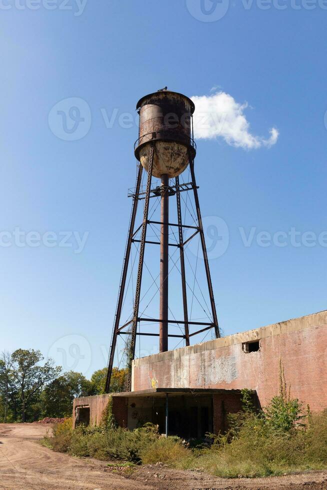 une magnifique l'eau la tour est ensemble autour un abandonné zone. cette rouillé métal structure des stands grand contre une bleu ciel. photo