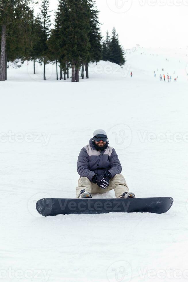 snowboarder séance à le Haut de une Montagne photo