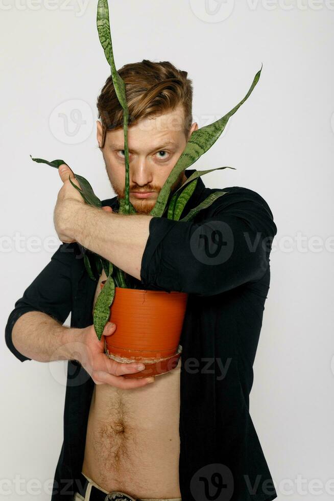 une Jeune souriant homme détient dans le sien mains une petit fleur photo