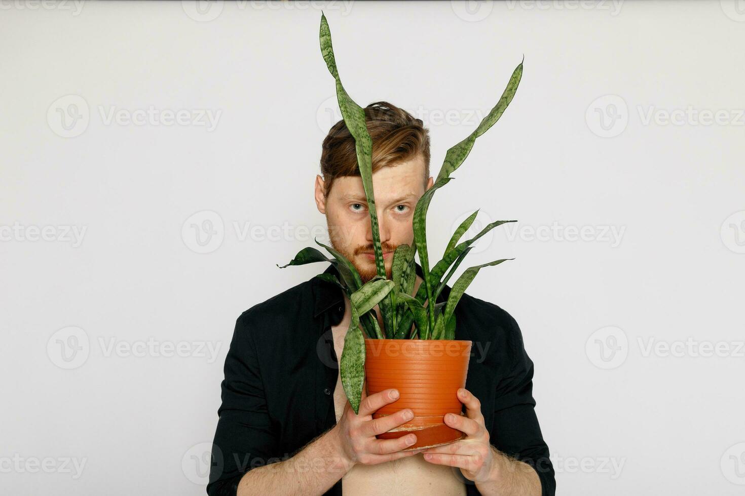 une Jeune souriant homme détient dans le sien mains une petit fleur photo