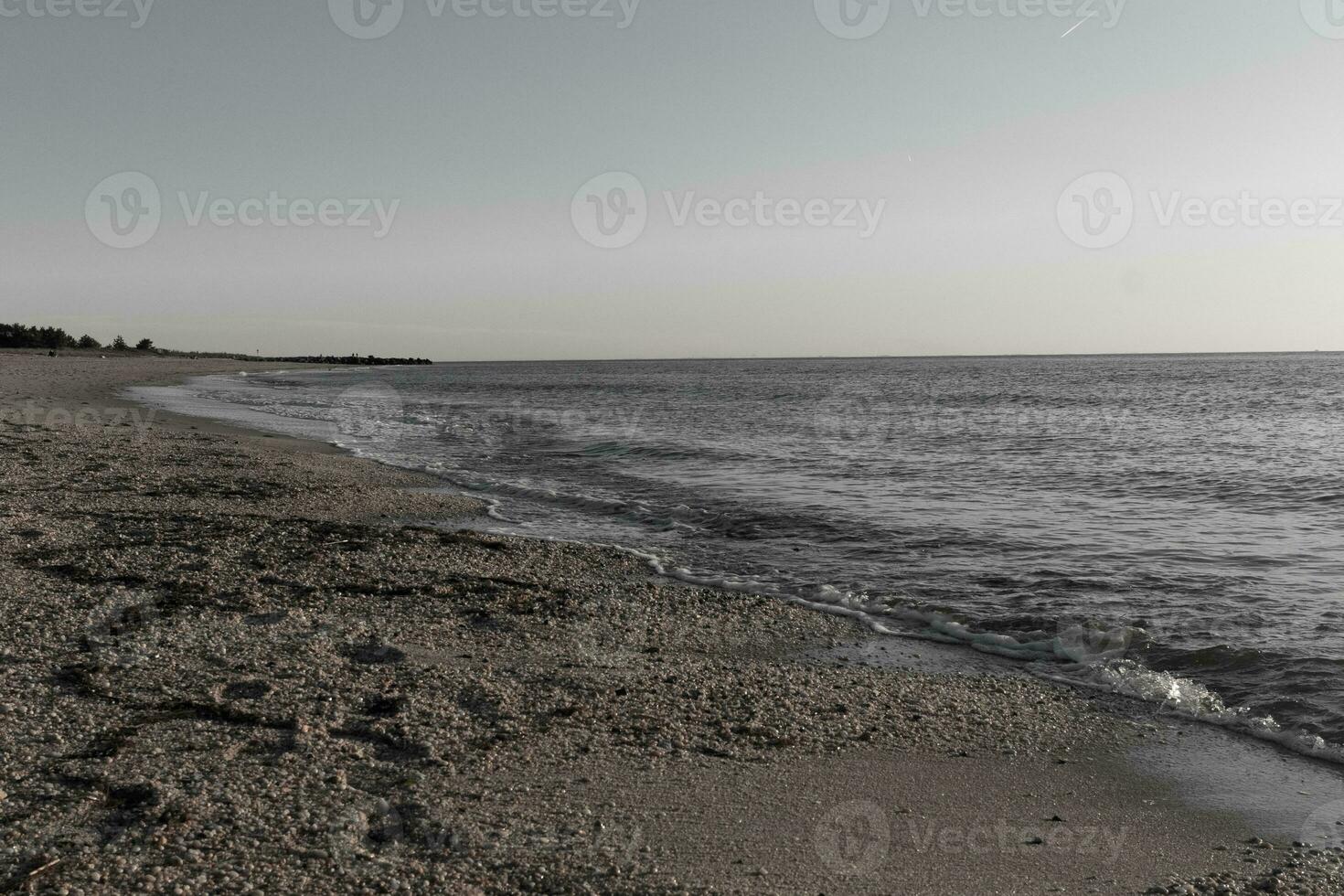 jolie Regardez de cette plage comme le vagues venu dans à le rive. le l'eau à la recherche calme et le le sable une d'or marron. le magnifique ciel avec non des nuages dans site fait du cette Regardez comme une magnifique été journée. photo