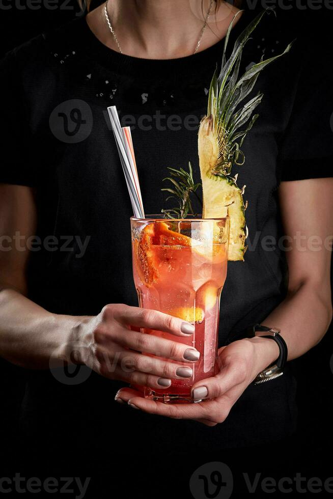 rose fruit cocktail ou limonade dans le mains de une femme dans une noir T-shirt. photo