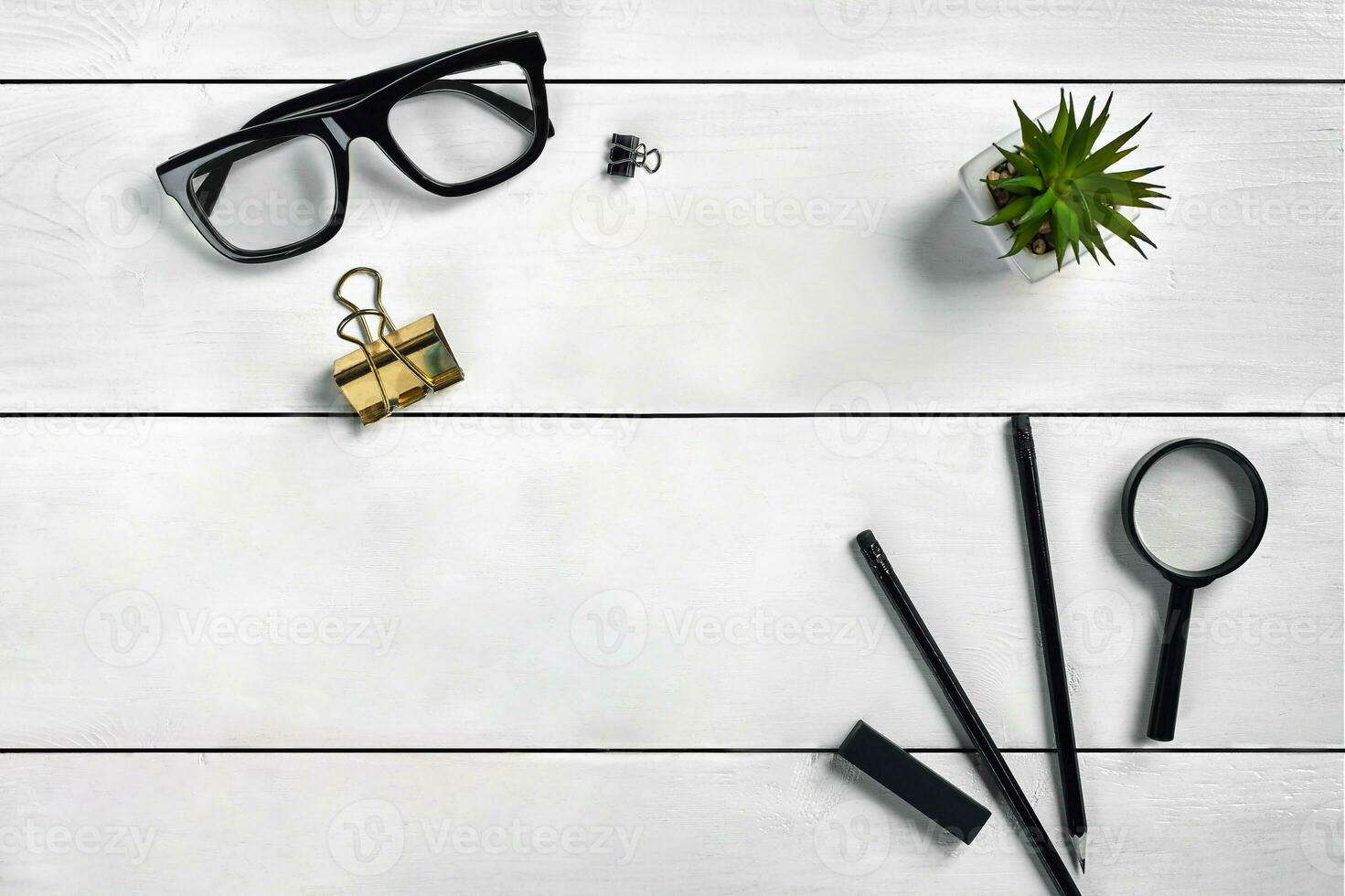 blanc en bois bureau avec lunettes, deux des crayons, agrafeuse, loupe, classeur agrafe et succulent dans une pot sur il. proche en haut, copie espace photo