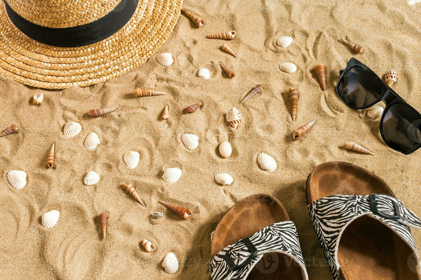 été tenue de plage, retourner flops, chapeau, des lunettes de soleil et coquillages sur le sable plage. photo