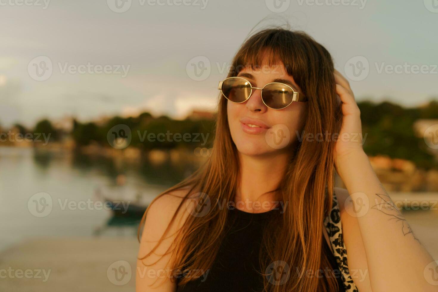 magnifique brunette femme avec élégant coiffure en marchant Extérieur sur le jetée. chaud soleil couchant couleurs. Voyage et vacances concept. photo