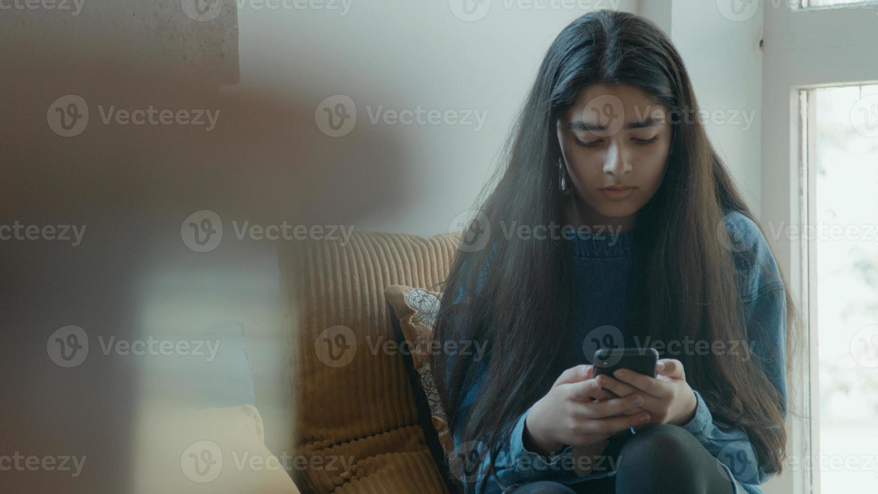 fille assise dans le coin regarde smartphone photo