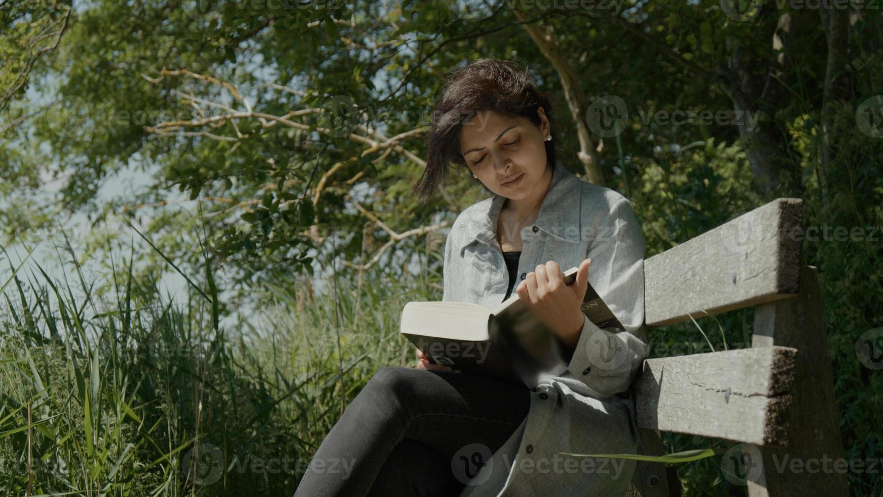 femme assise sur un banc en bois dans le pays lisant un livre photo