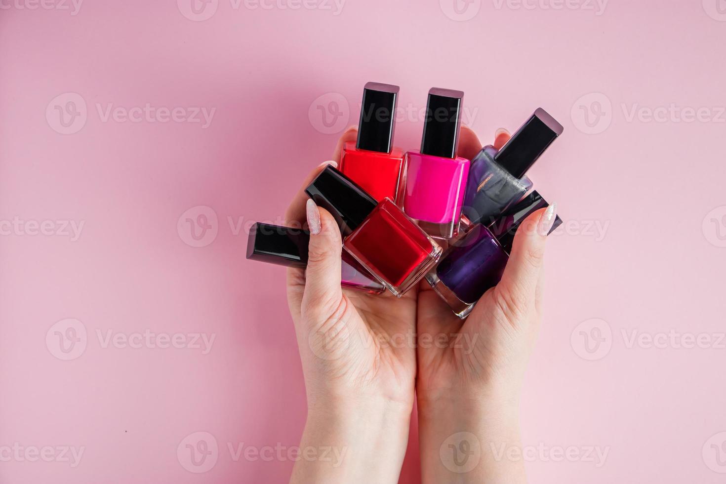 mains avec des vernis à ongles brillants. groupe de vernis à ongles coloré photo