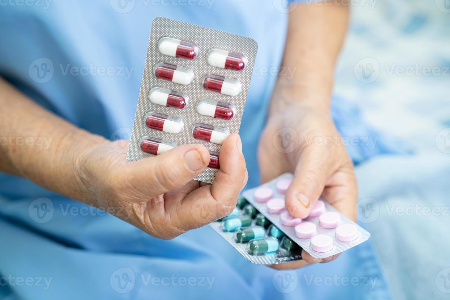 Asian senior woman patient holding pills sous blister photo