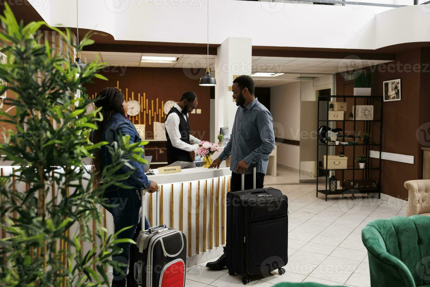 content noir couple permanent à Hôtel de face bureau avec bagage, vérification dans à voyage de noces station balnéaire, gens attendre à accueil pour enregistrement. réceptionniste portion invités avec vérifier en dehors photo