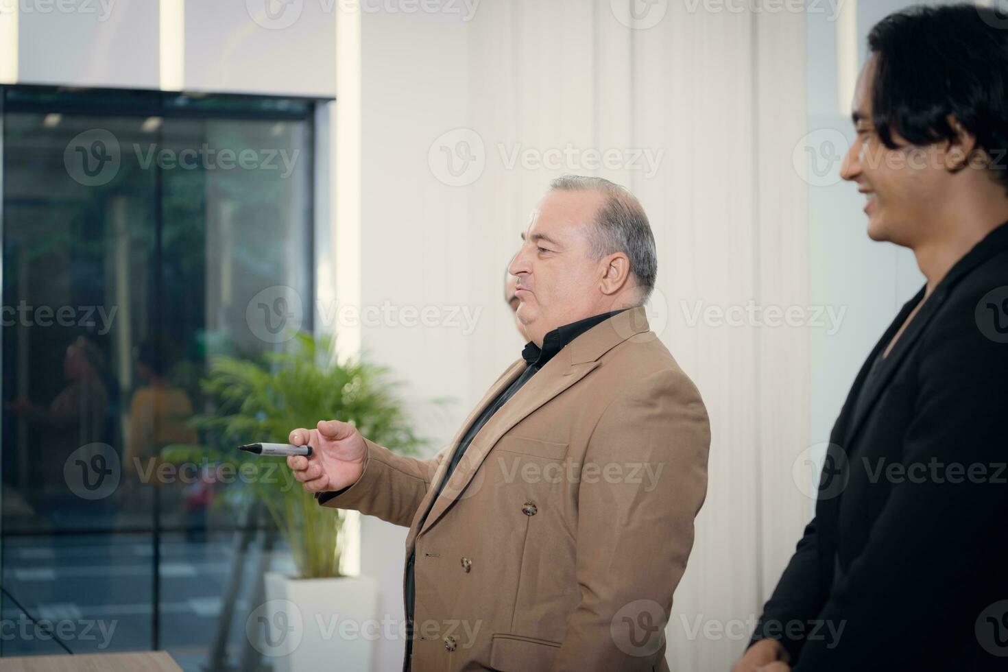 portrait de une Sénior homme d'affaire donnant une présentation à le sien collègue à Bureau photo