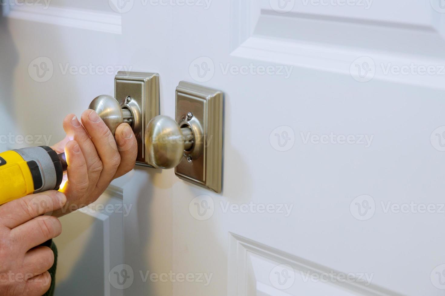 le maître avec un tournevis installe une nouvelle serrure factice dans la maison. photo