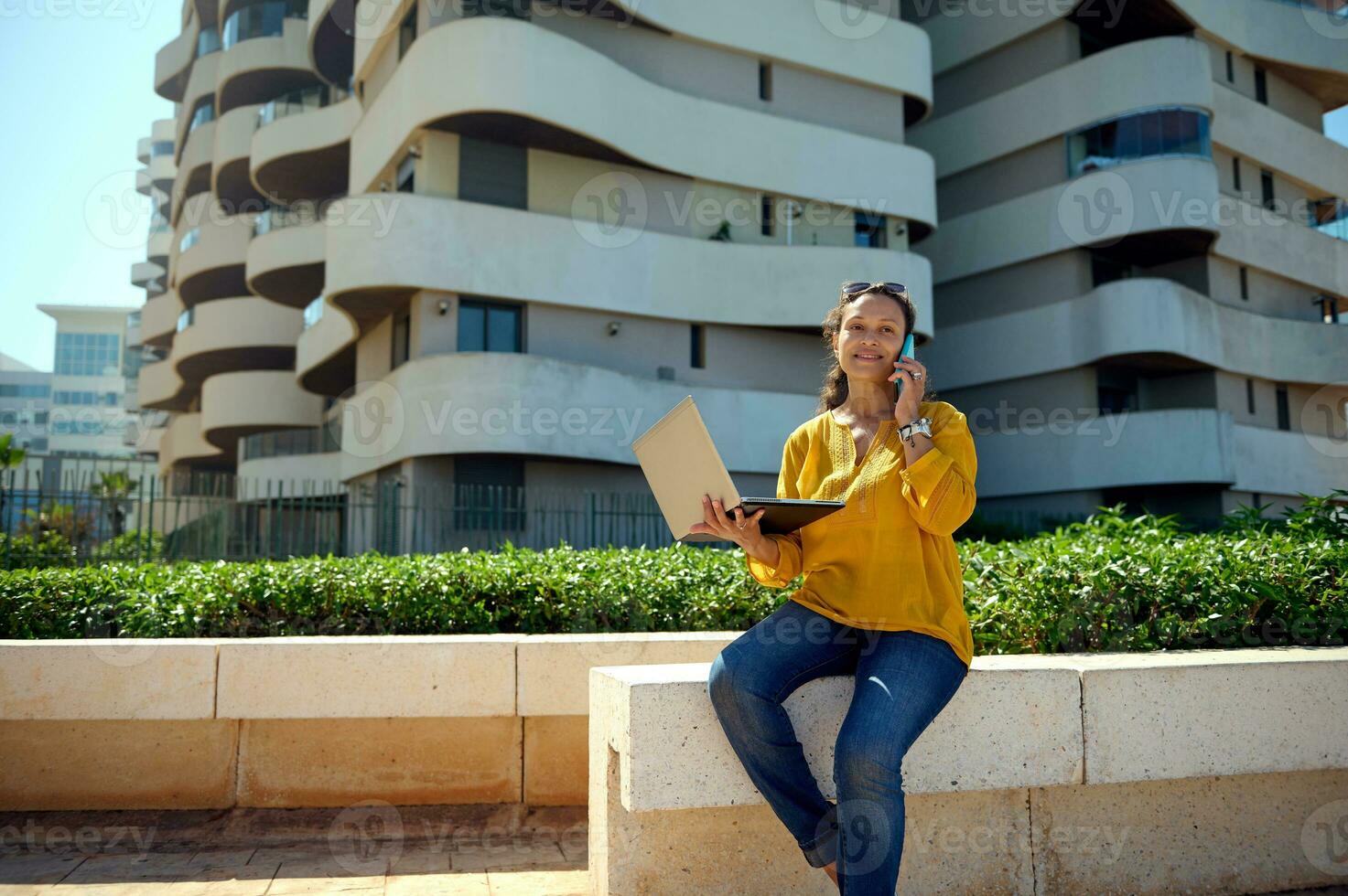 femelle étudiant détient une portable et pourparlers sur mobile téléphone, travaux sur Nouveau diplôme projet Extérieur. personnes. en ligne éducation photo