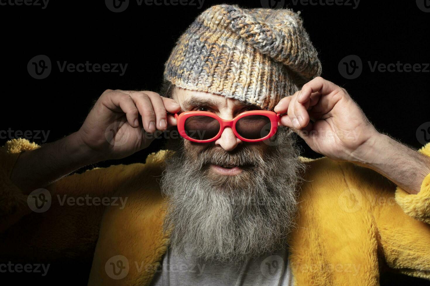 à la mode personnes âgées barbu homme dans brillant vêtements sur une noir Contexte. photo