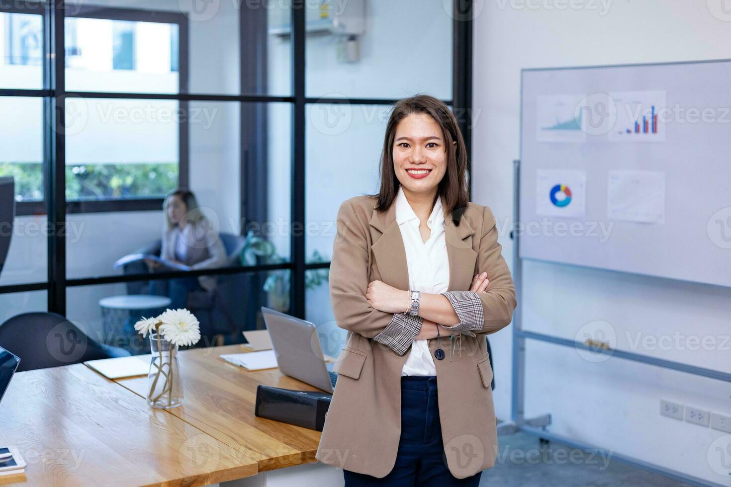 portrait de asiatique affaires PDG femme est permanent crosshand dans sa Bureau à le table avec statistique graphique montrant annuel rapport photo