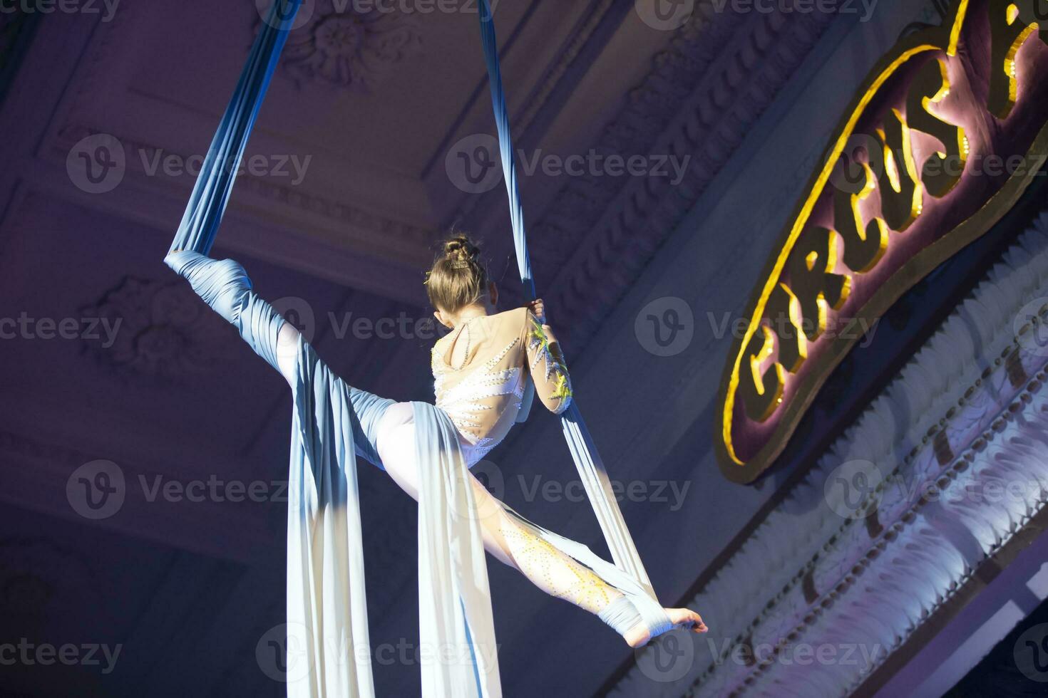 le fille effectue acrobatique Nombres sur le toiles. une petit cirque artiste effectue sur le toiles de acrobates. enfant effectuer acrobatique éléments dans le air photo