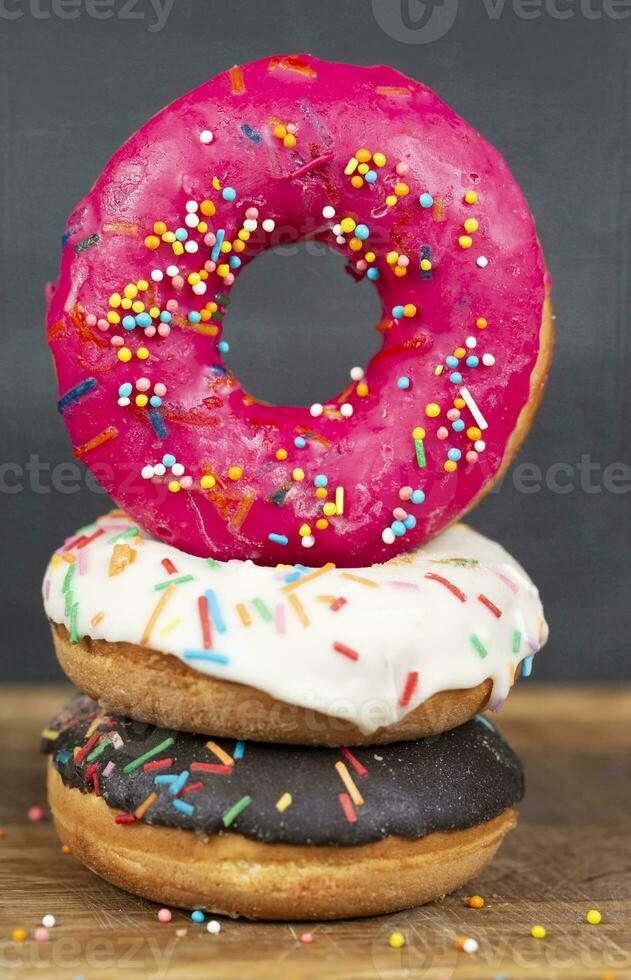 charmant sucré aliments. empiler de vitré coloré assorti beignets avec éclaboussures sur une gris Contexte. photo