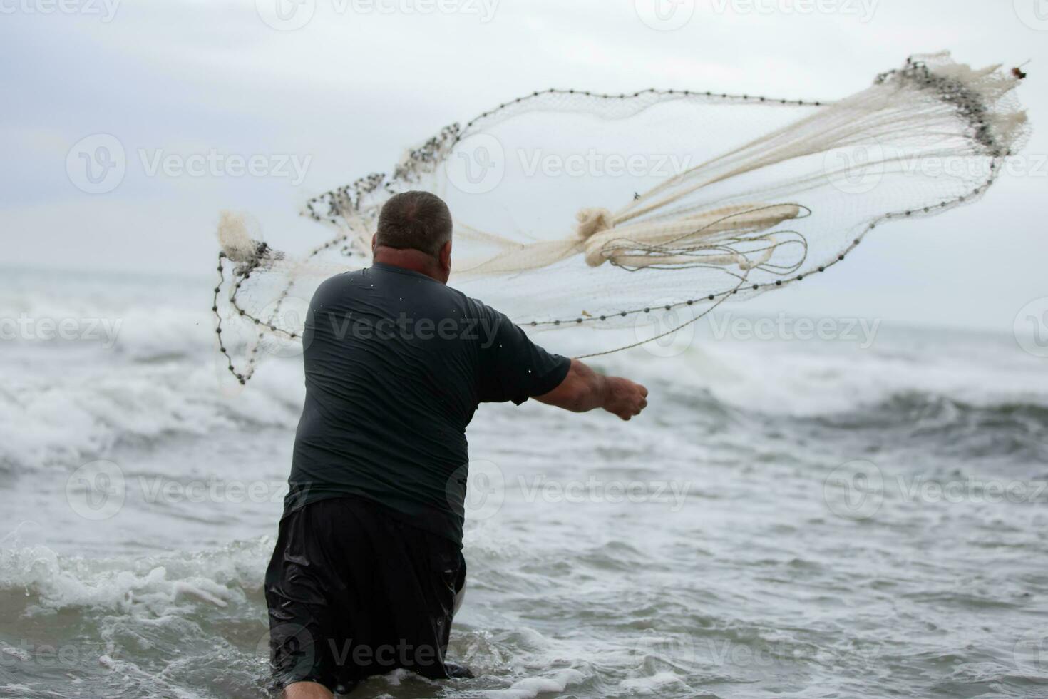 une pêcheur jette une pêche net dans le mer. photo