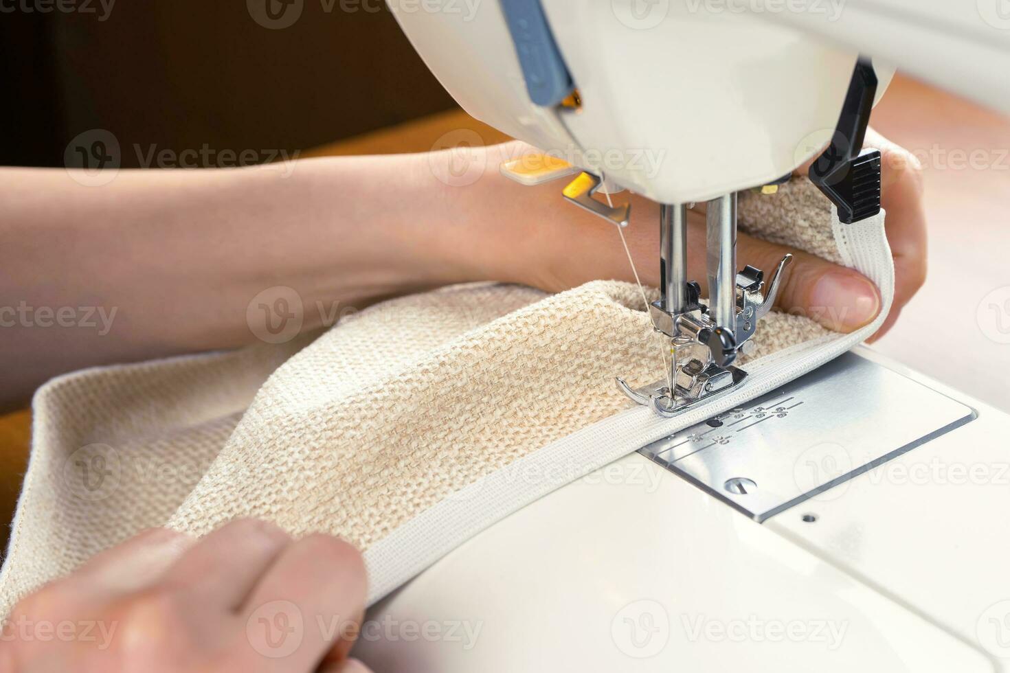 femelle mains piqûre blanc en tissu sur moderne couture machine. proche en haut vue de couture processus. photo