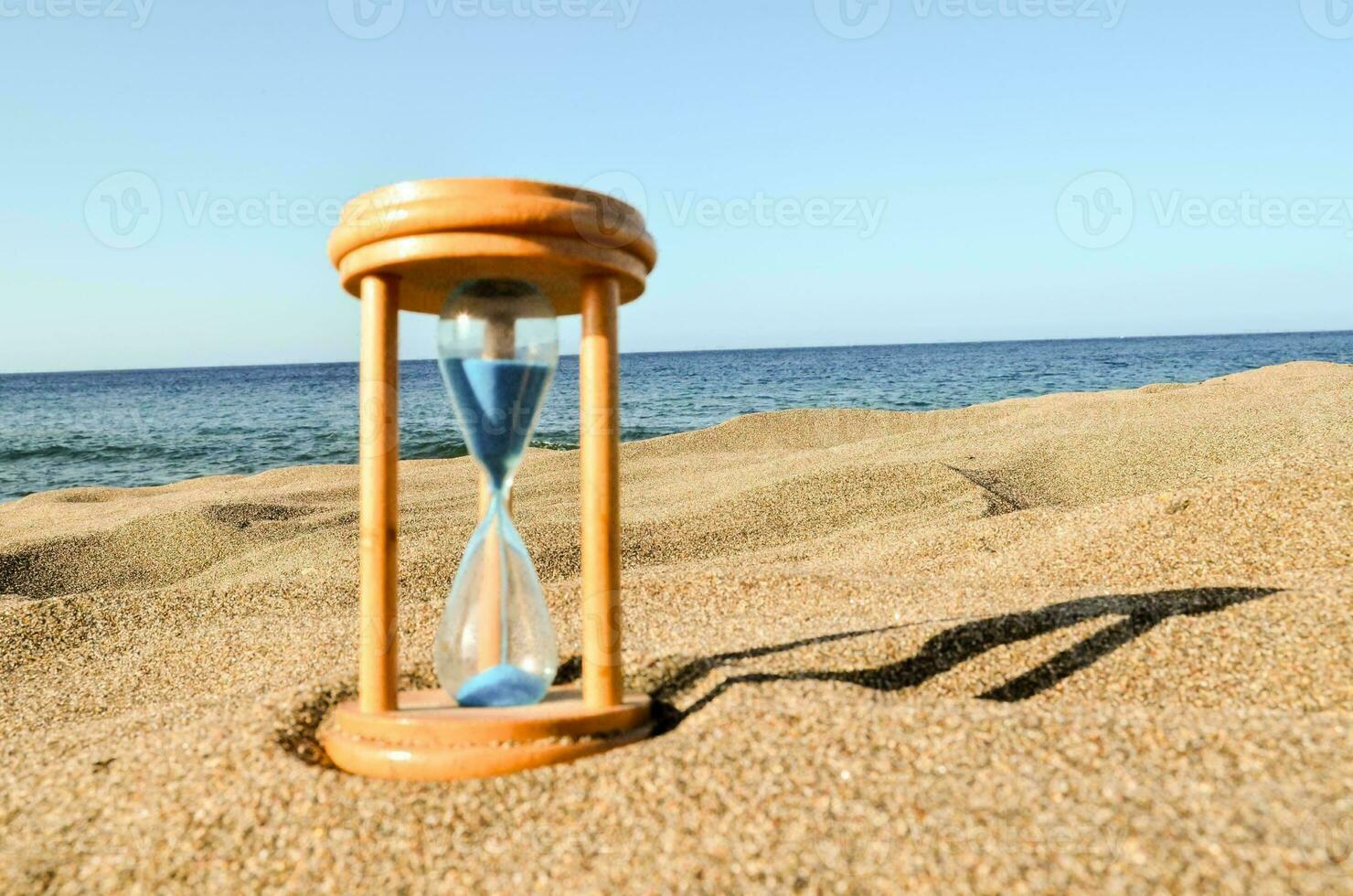 un Sablier avec bleu le sable sur le plage photo