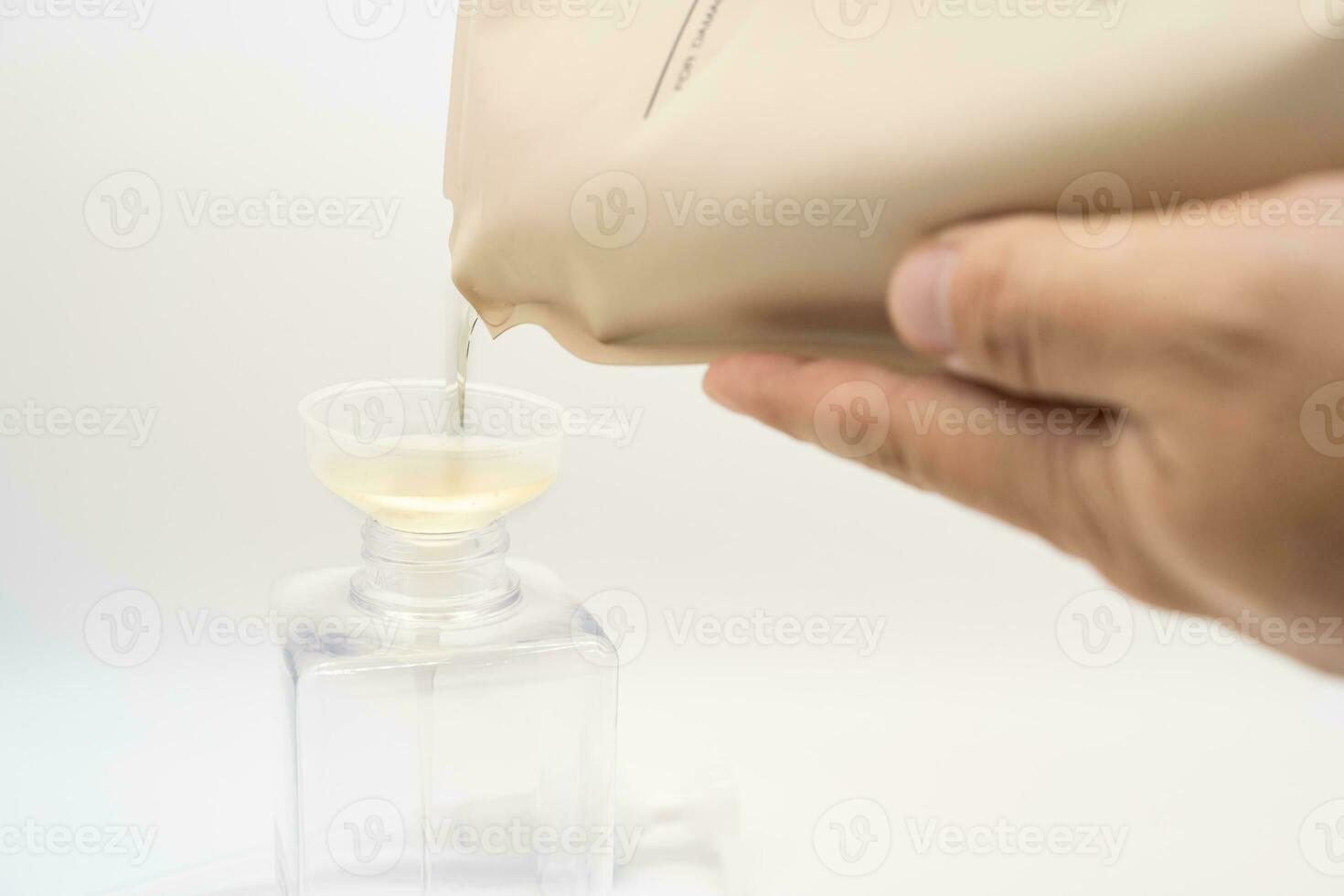 une homme remplit une distributeur avec liquide savon par verser il de une recharge à réduire Plastique déchets. savon ou shampooing pour recharge. photo