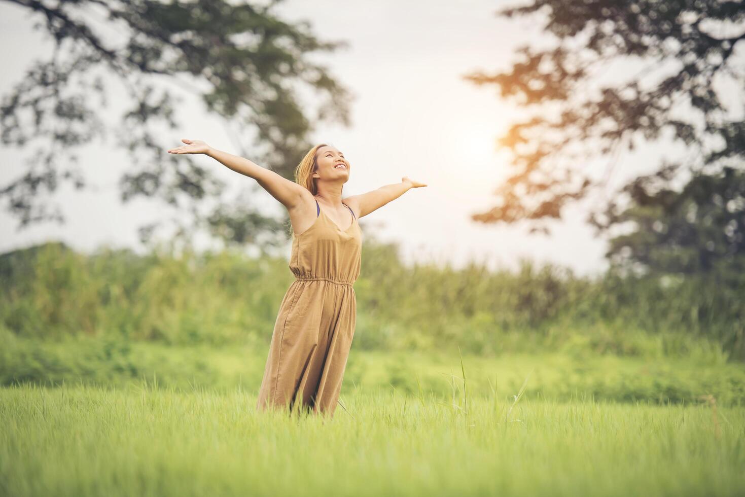 jeune femme debout dans le champ d'herbe levant les mains en l'air. photo