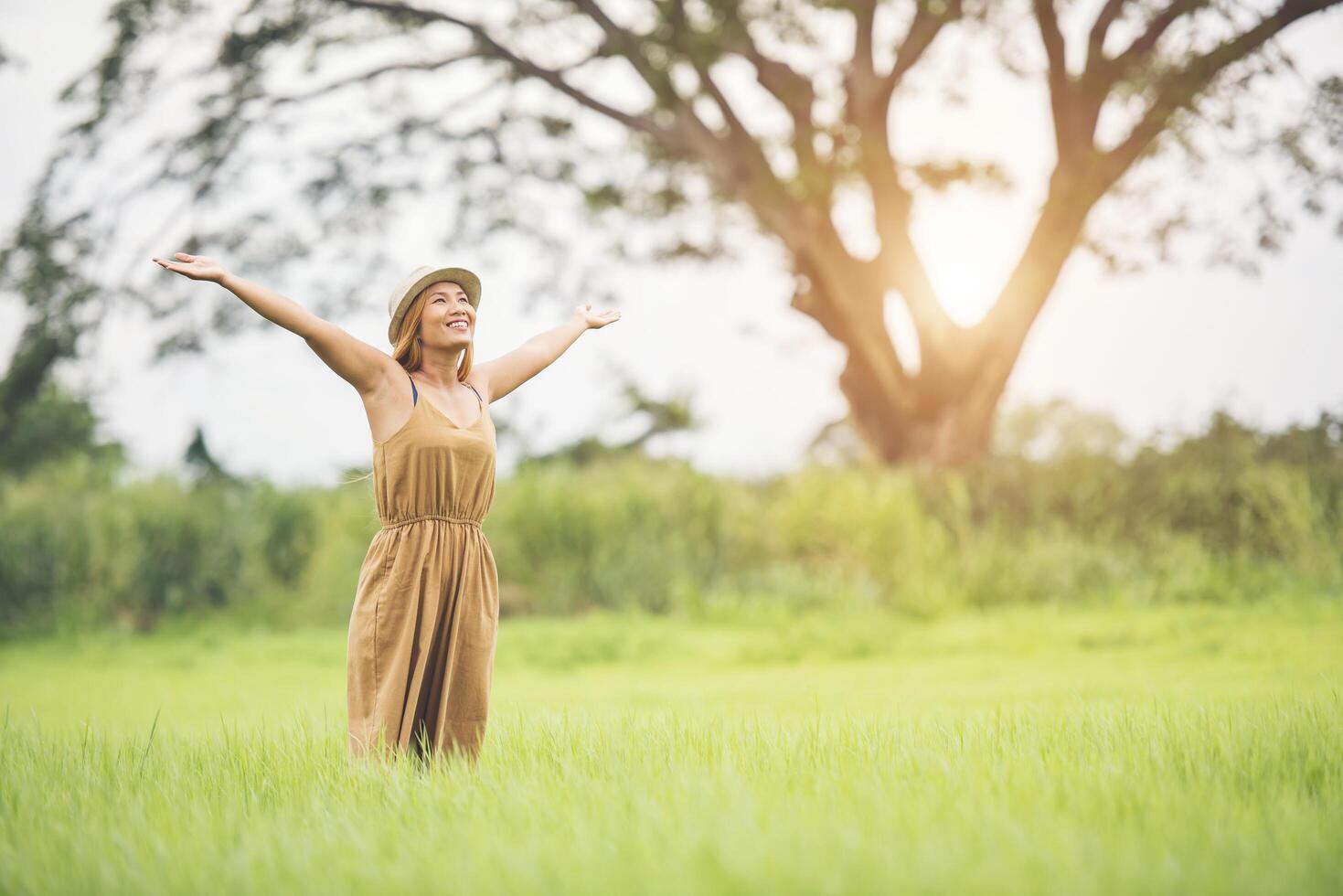 jeune femme debout dans le champ d'herbe levant les mains en l'air. photo
