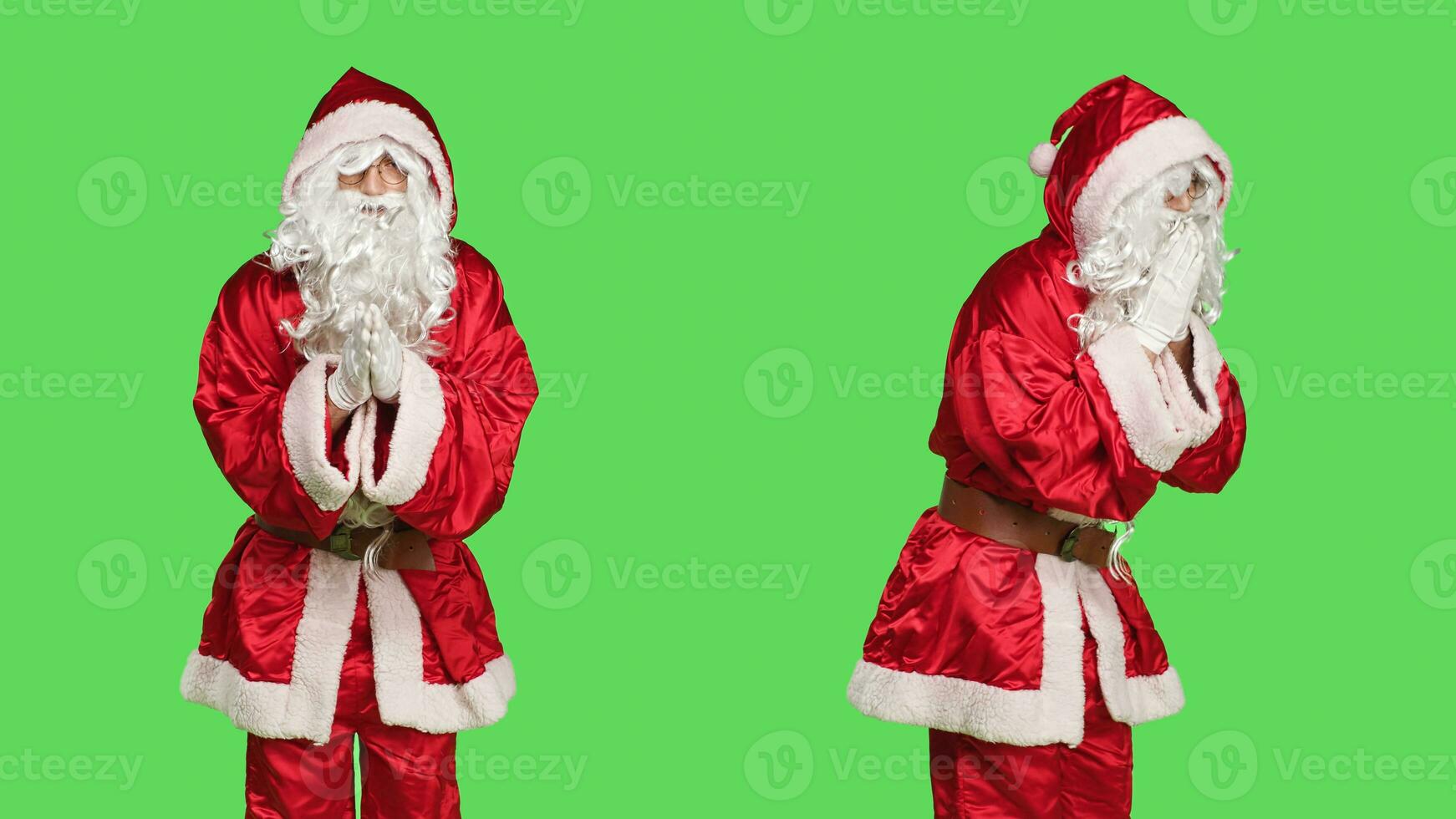 Saint pseudo personnage prier sur caméra, en portant mains dans une prière et posant sur écran vert pendant vacances saison. Jeune homme habillé comme Père Noël claus agissant spirituel et religieux. photo