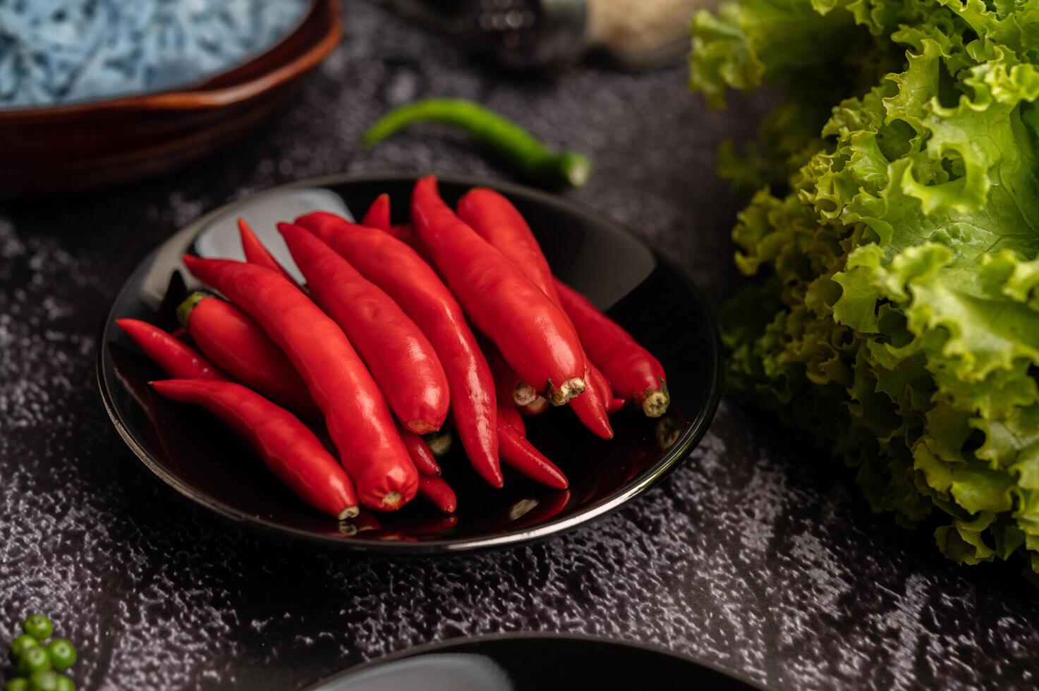 piments dans une assiette noire avec de la laitue sur un sol en ciment photo