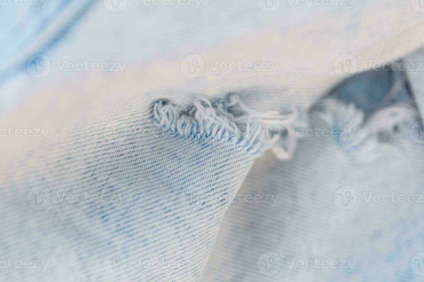 à la mode lumière déchiré jeans texture, fermer. élégant déchiré denim en tissu photo