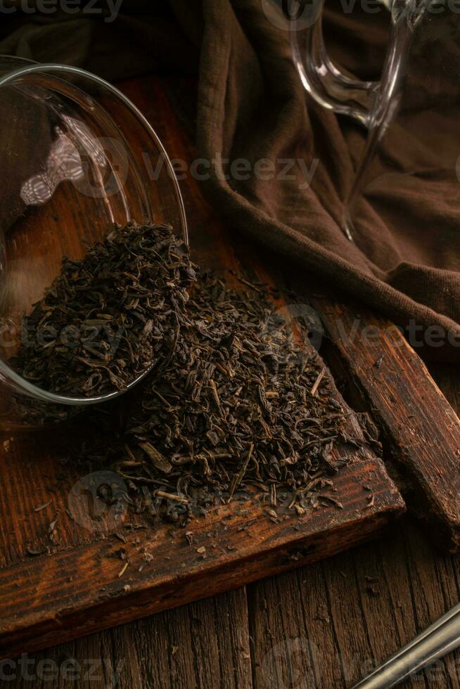 macro la photographie de délicieux salé thé feuilles déversé de verre pot sur en bois ancien planche sur marron foncé Contexte photo
