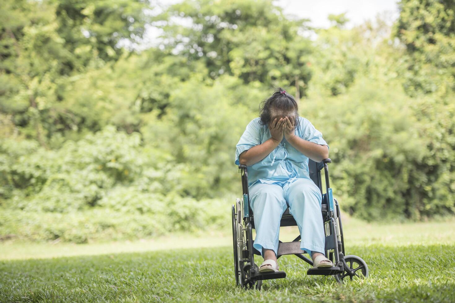 Femme âgée seule assise triste sentiment sur fauteuil roulant au jardin photo