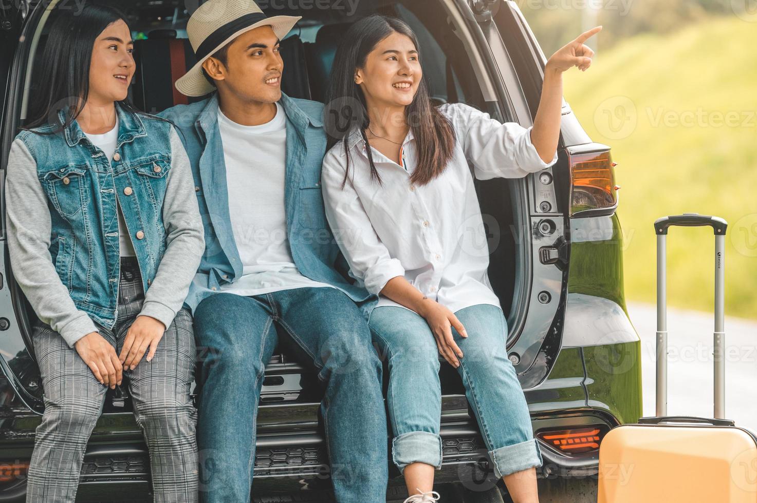 homme et femmes asiatiques se relaxant à l'arrière du coffre de la voiture pendant le voyage photo