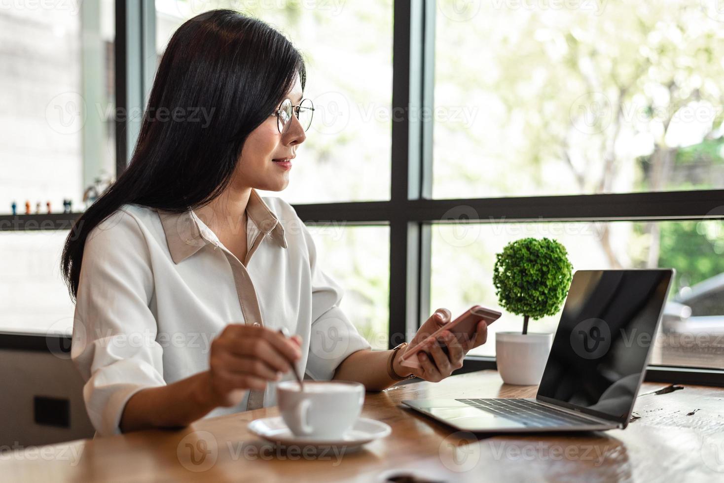 femme d'affaires travaillant avec un ordinateur portable et un smartphone et buvant du café photo