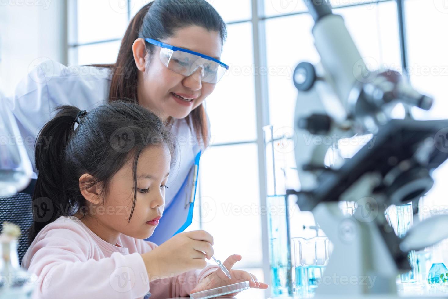 fille scientifique et enseignant laissant tomber la pipette liquide de substance de solution photo