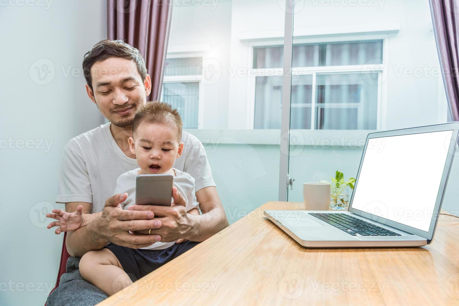 père et fils asiatiques utilisant un téléphone intelligent ensemble à la maison photo