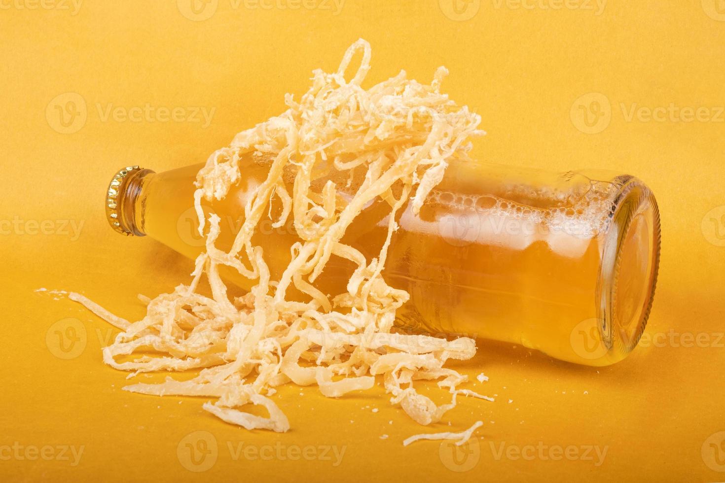 une bouteille de bière légère avec des calmars séchés sur fond jaune photo