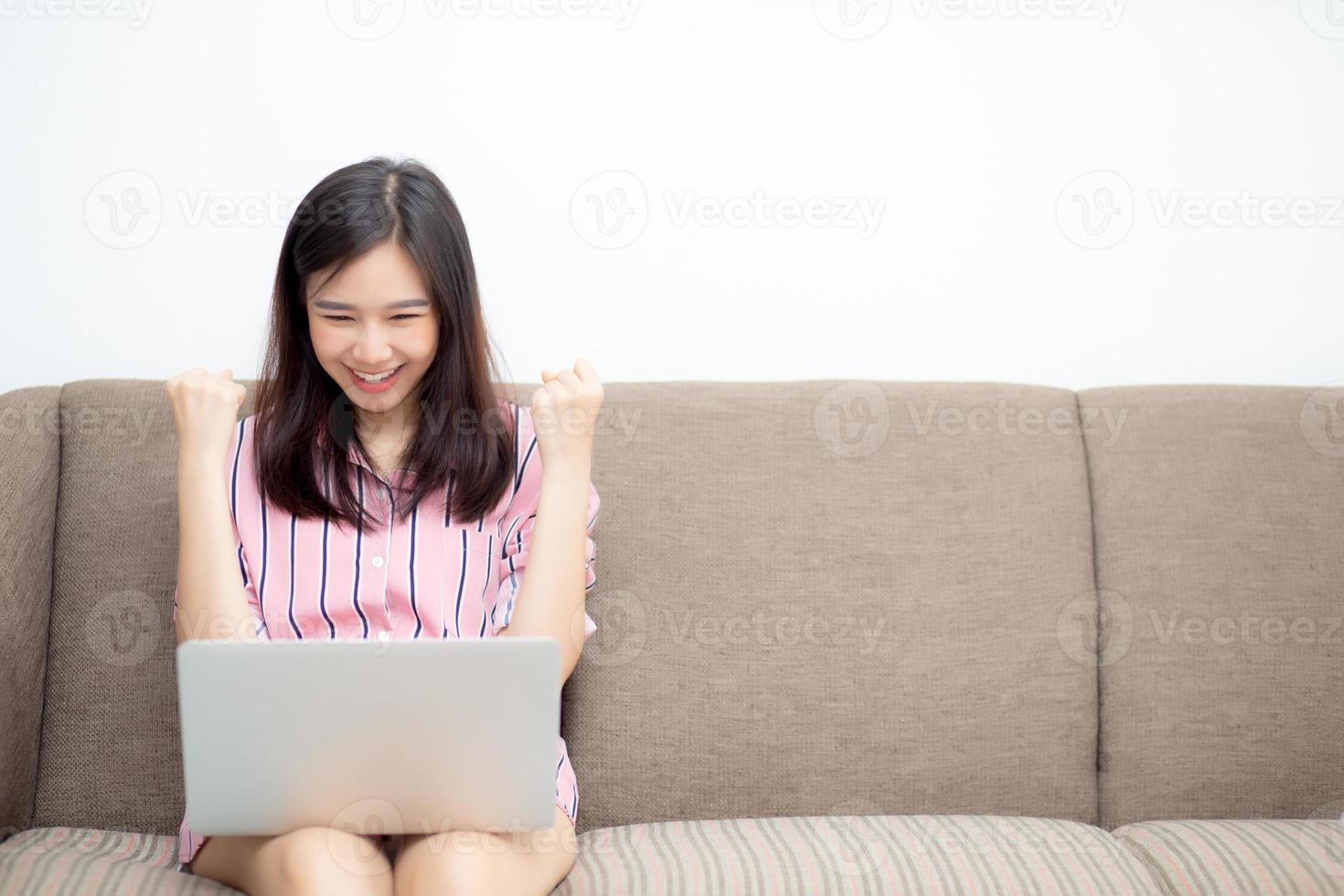 jeune femme asiatique excitée et heureuse du succès avec un ordinateur portable. photo
