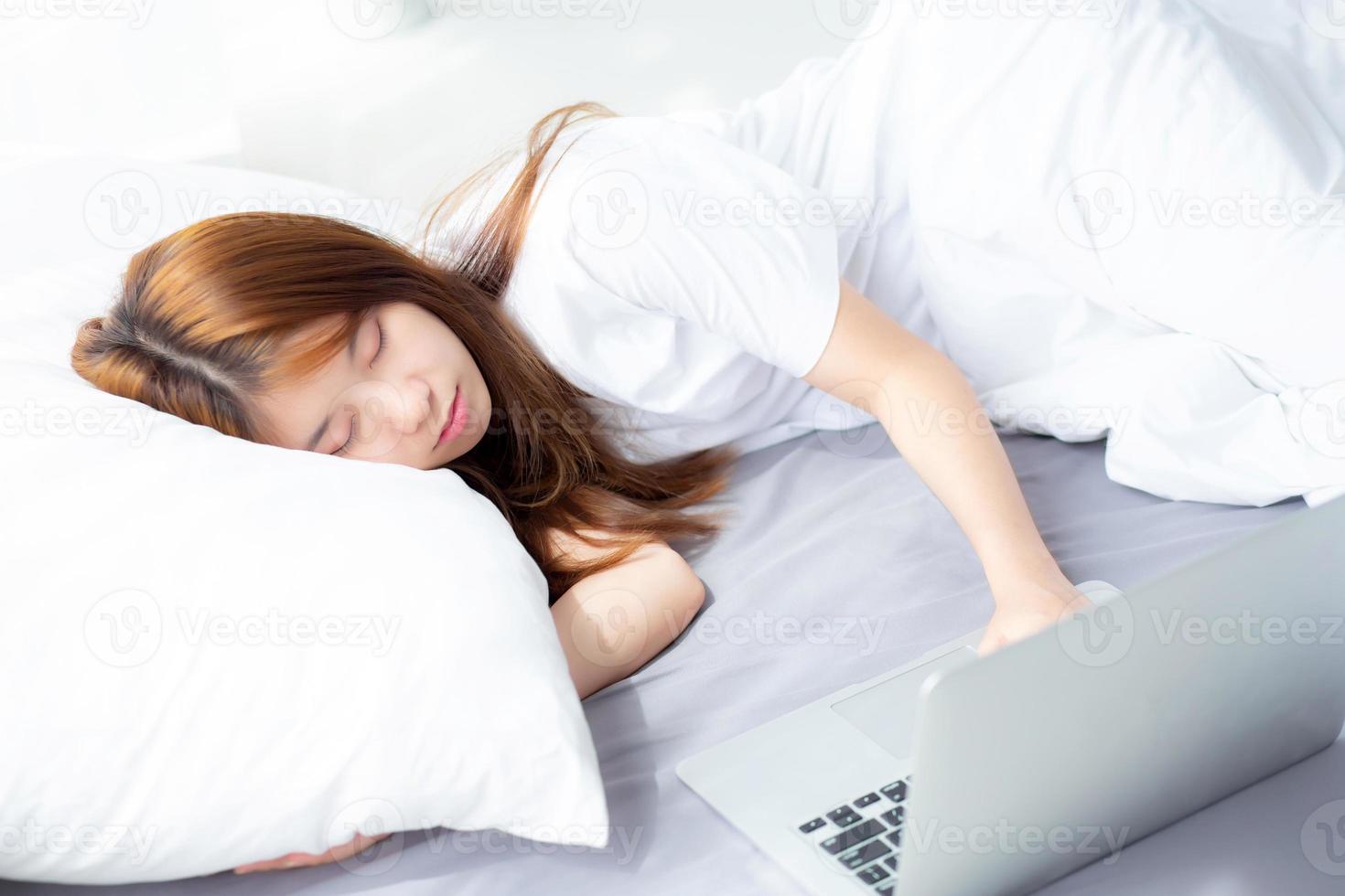 jeune femme asiatique avec ordinateur portable couché dans la chambre. photo
