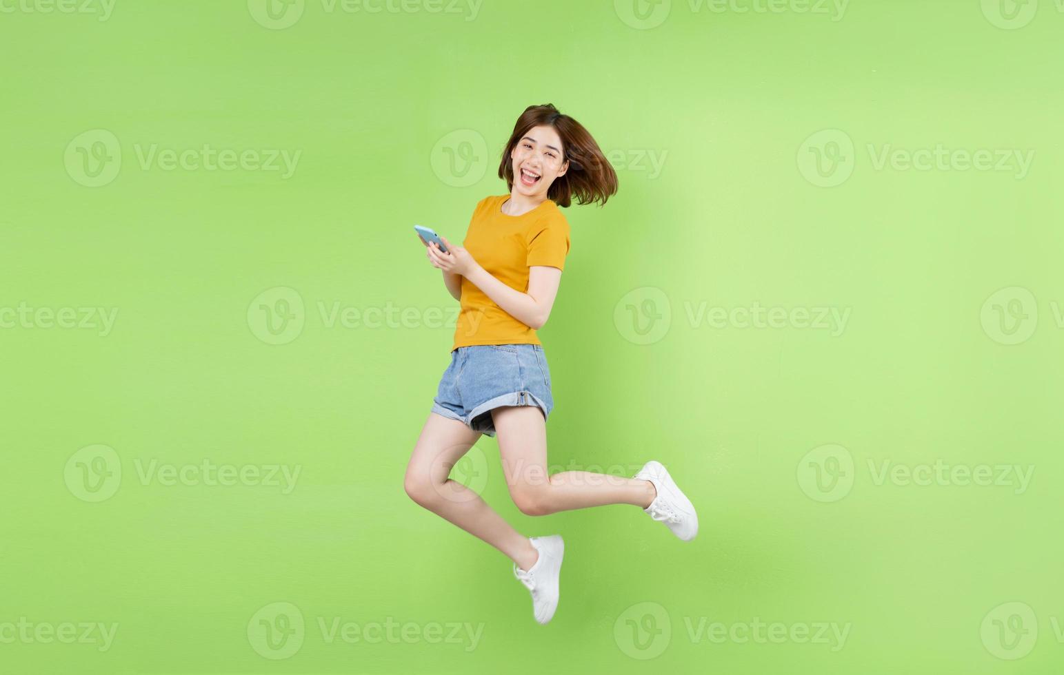 jeune fille asiatique sautant sur un fond vert photo