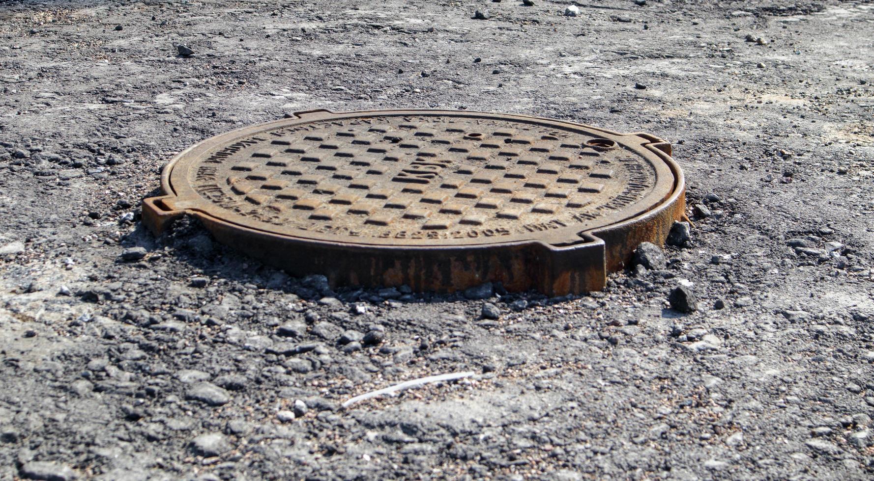 trou d'homme en métal sur la route lors du pavage d'un nouvel asphalte. photo