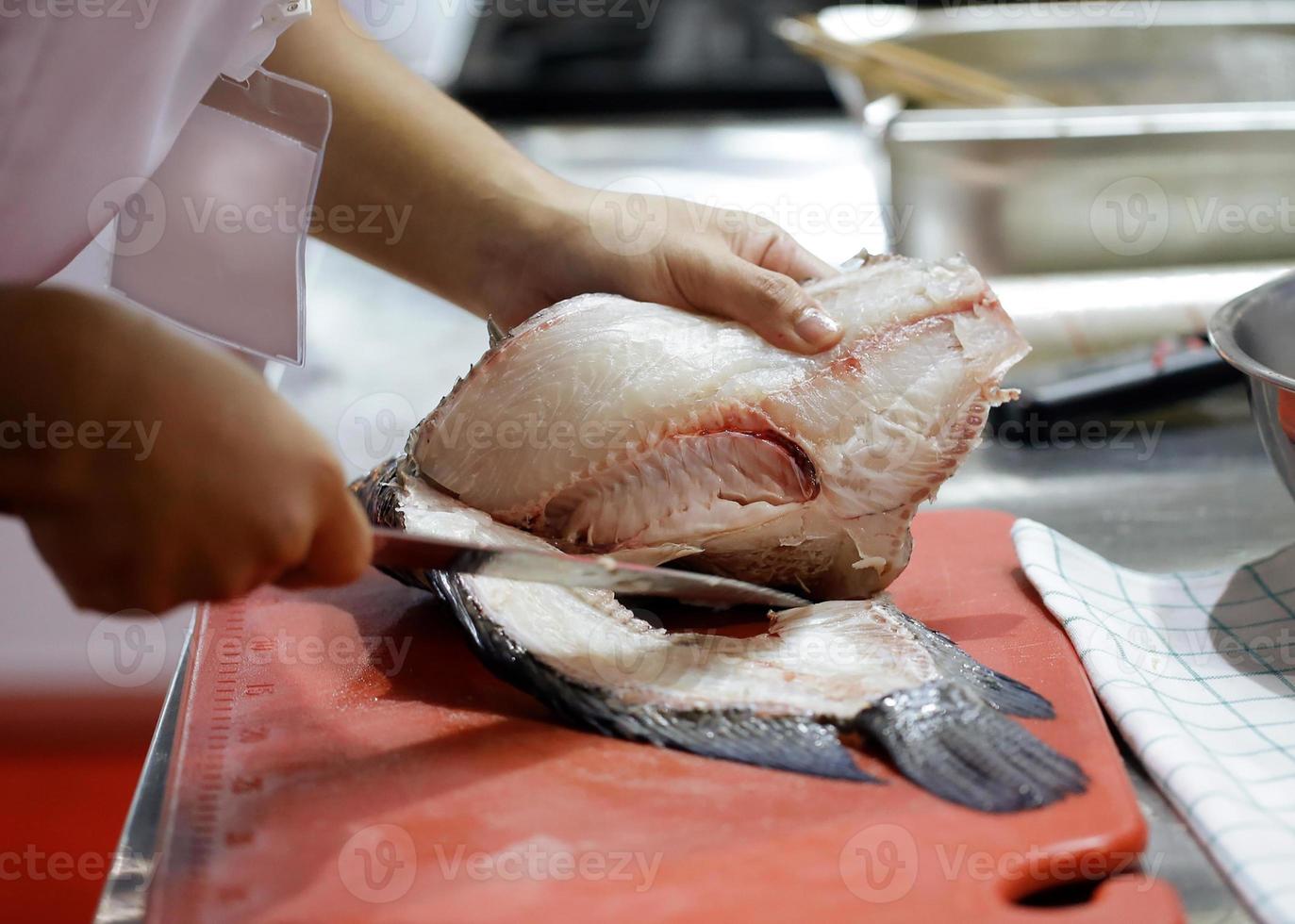chef coupant du poisson, le chef tranche du poisson frais à bord dans la cuisine photo