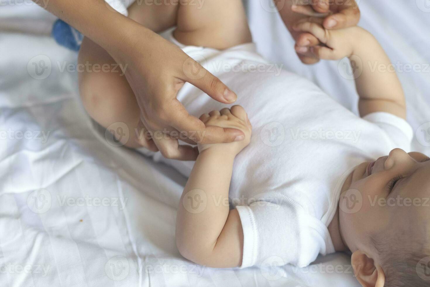 bébé massage. maman Faire gymnastique avec enfant. maman masser mignonne bébé garçon. en mouvement de bébé jambes à Aidez-moi soulager constipation. Jeune mère Faire des exercices et mouvements à stimuler de bébé intestins. photo