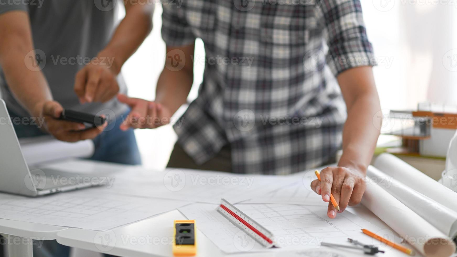 des architectes tenant des crayons et une calculatrice examinent le plan de la maison. photo