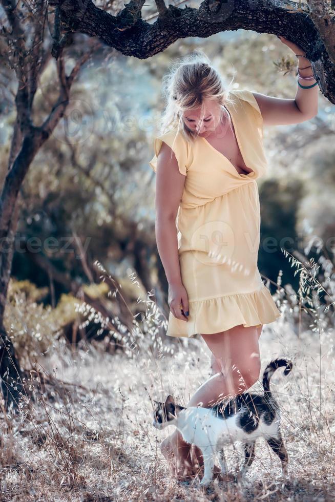une femme blonde aux pieds nus dans une robe d'été jaune photo