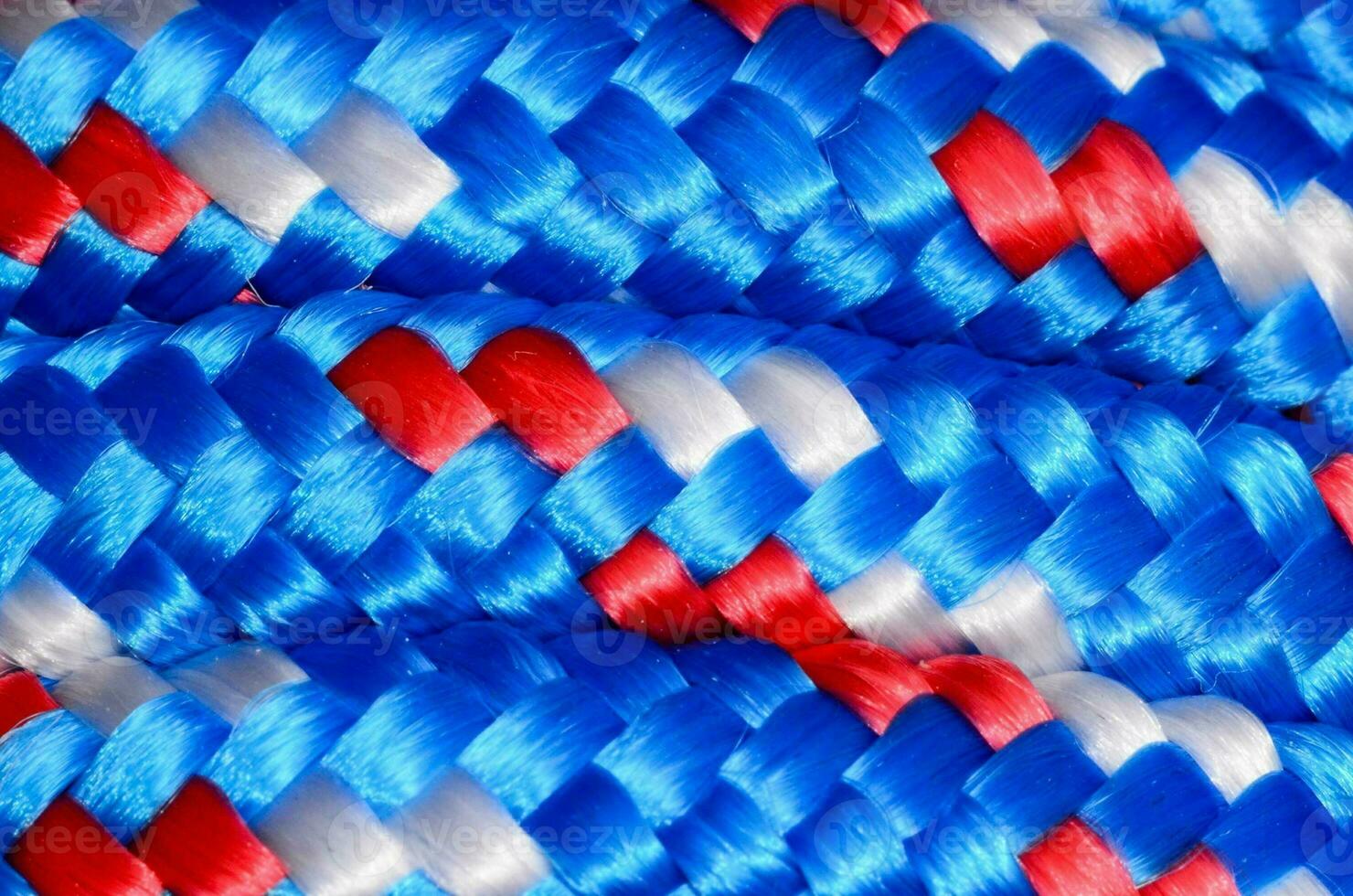 une proche en haut de une bleu, blanc et rouge tressé corde photo